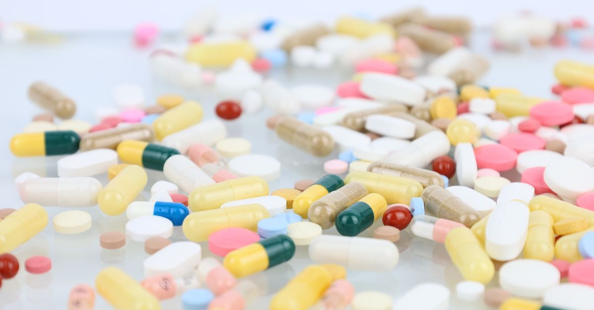 A vibrant assortment of pills and capsules scattered across a white surface representing medication and healthcare.